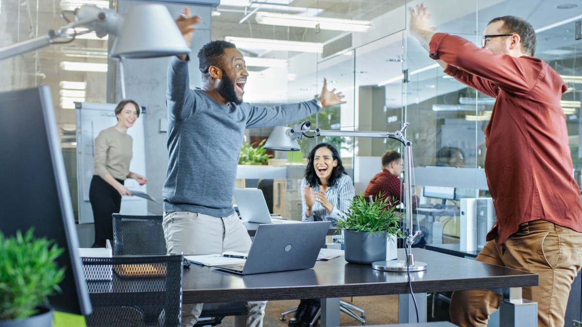 Multicultural coworkers excited about achievement celebrating 70s slang