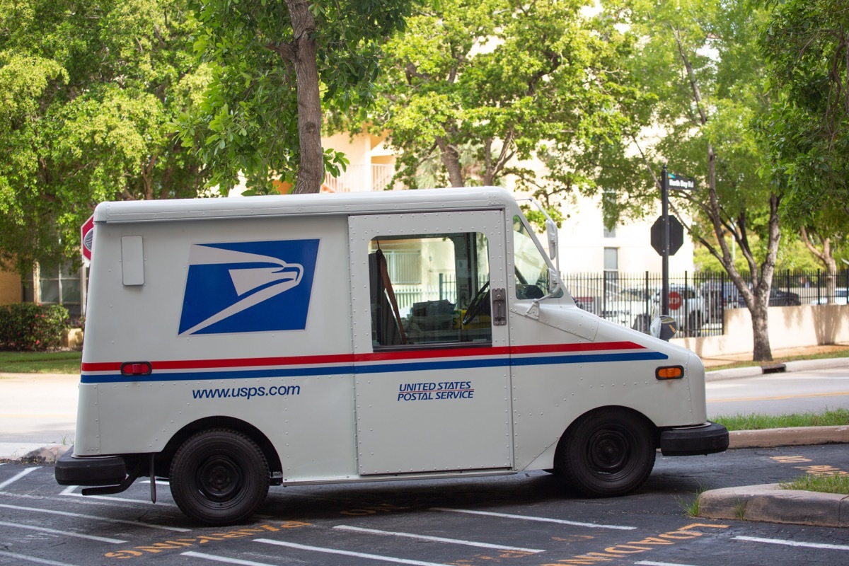 USPS truck parked on street with trees