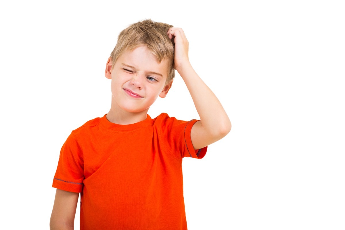 little boy in red shirt scratching his head