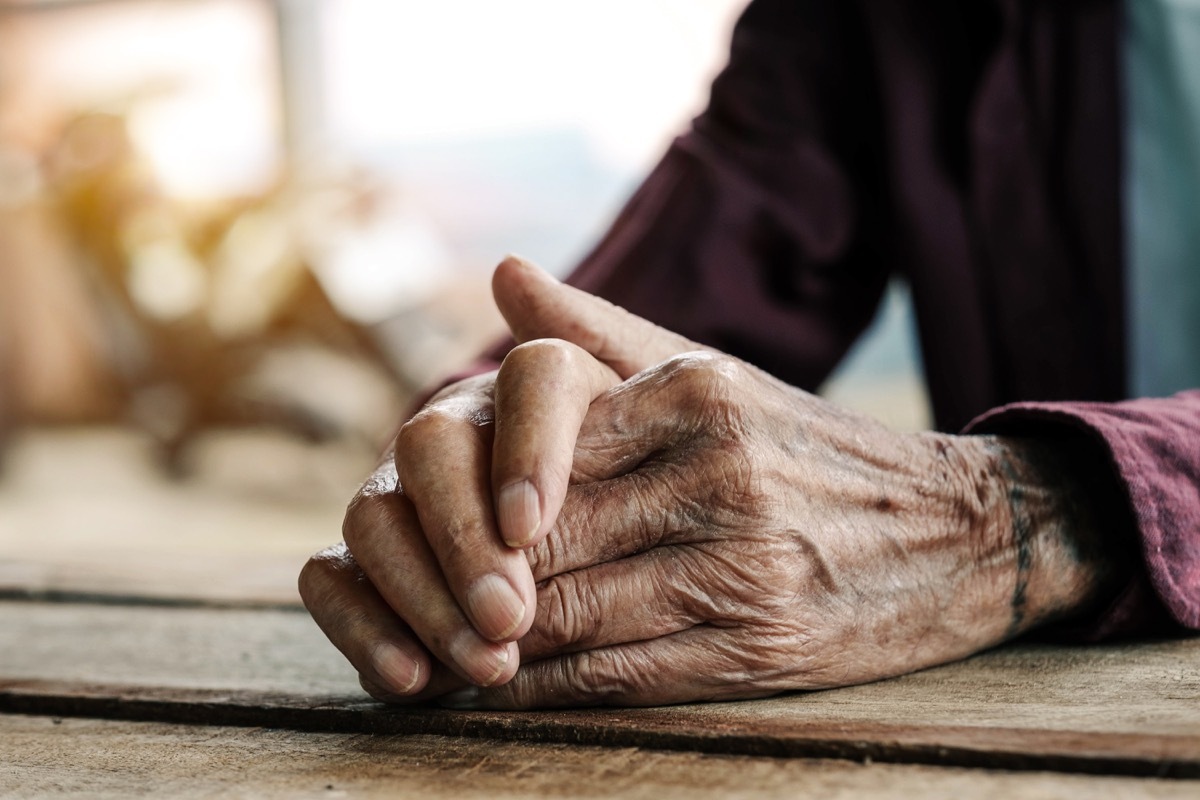 Hands of an old man on the wood table.vintage tone - Image