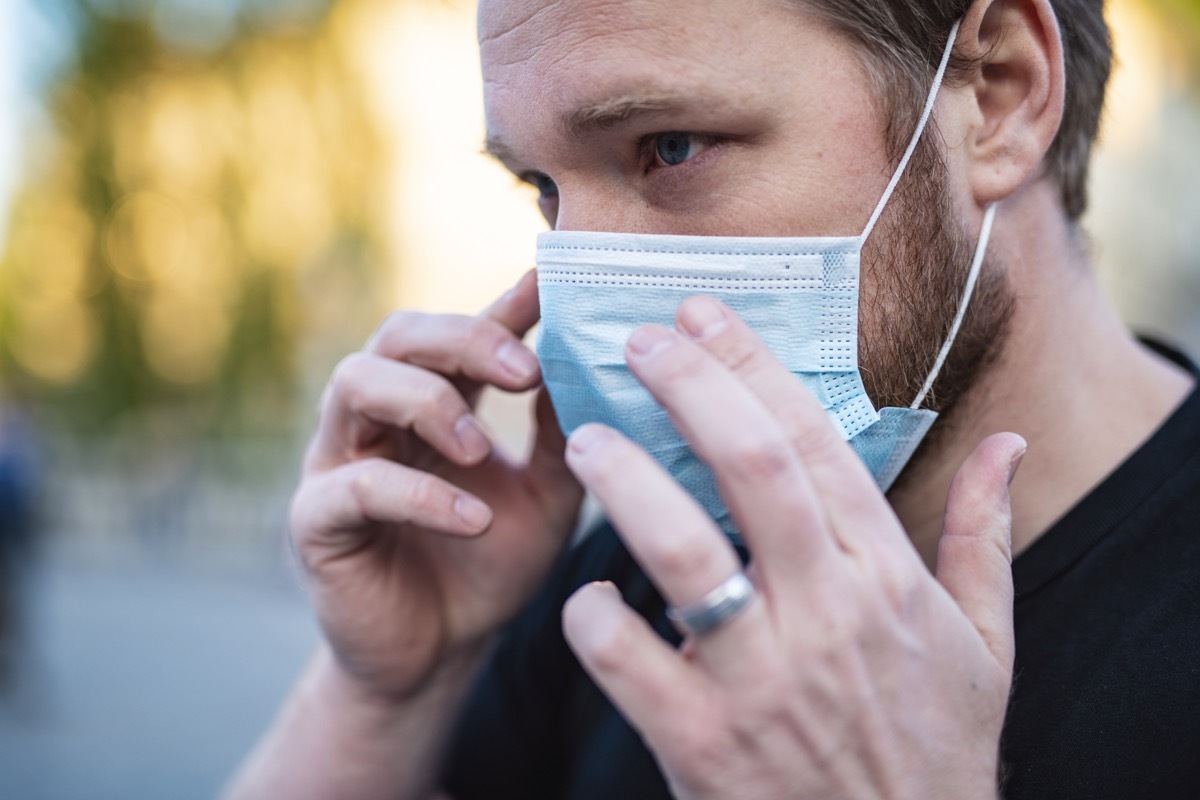 Man Putting On Face Mask In The City To Prevent Getting Coronavirus, COVID-19