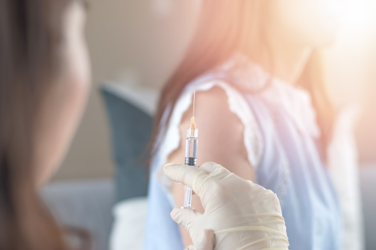 World immunization week and International HPV awareness day concept. Woman having vaccination for influenza or flu shot or HPV prevention with syringe by nurse or medical officer.