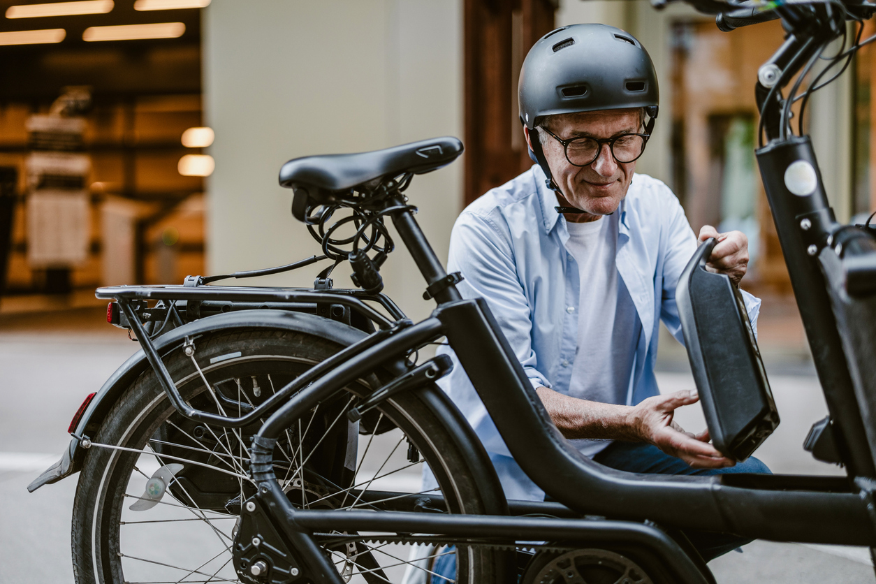 A senior man attaching a battery to an e-bike