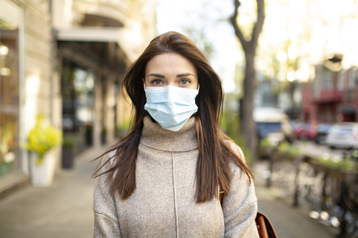 A young woman wearing a face mask in public to protect herself from COVID-19