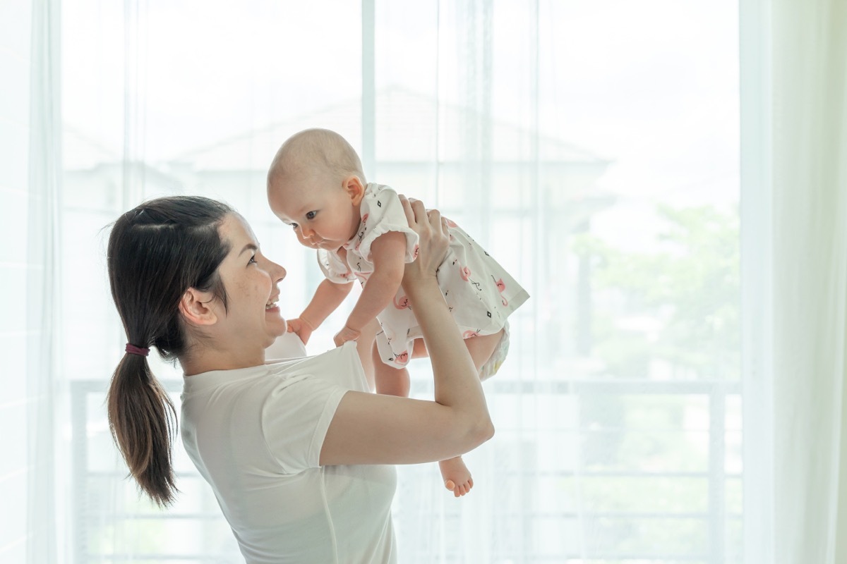 young asian mother holding baby in dress