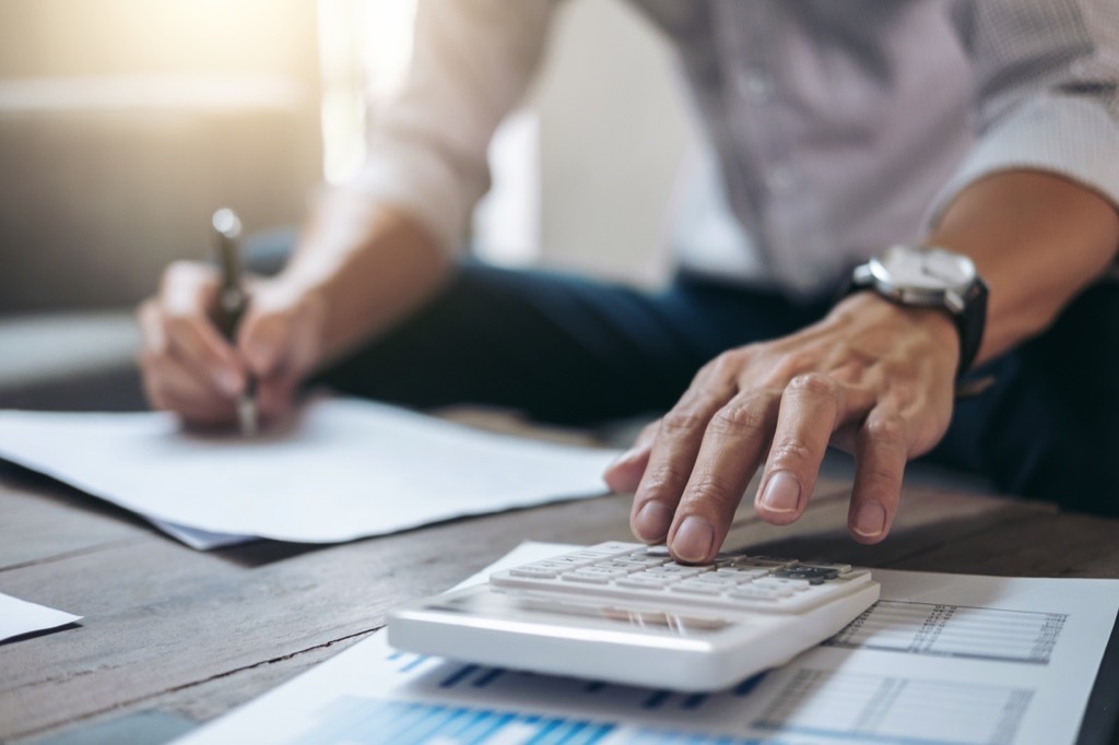 man doing finance paperwork with a calculator at a coffee table