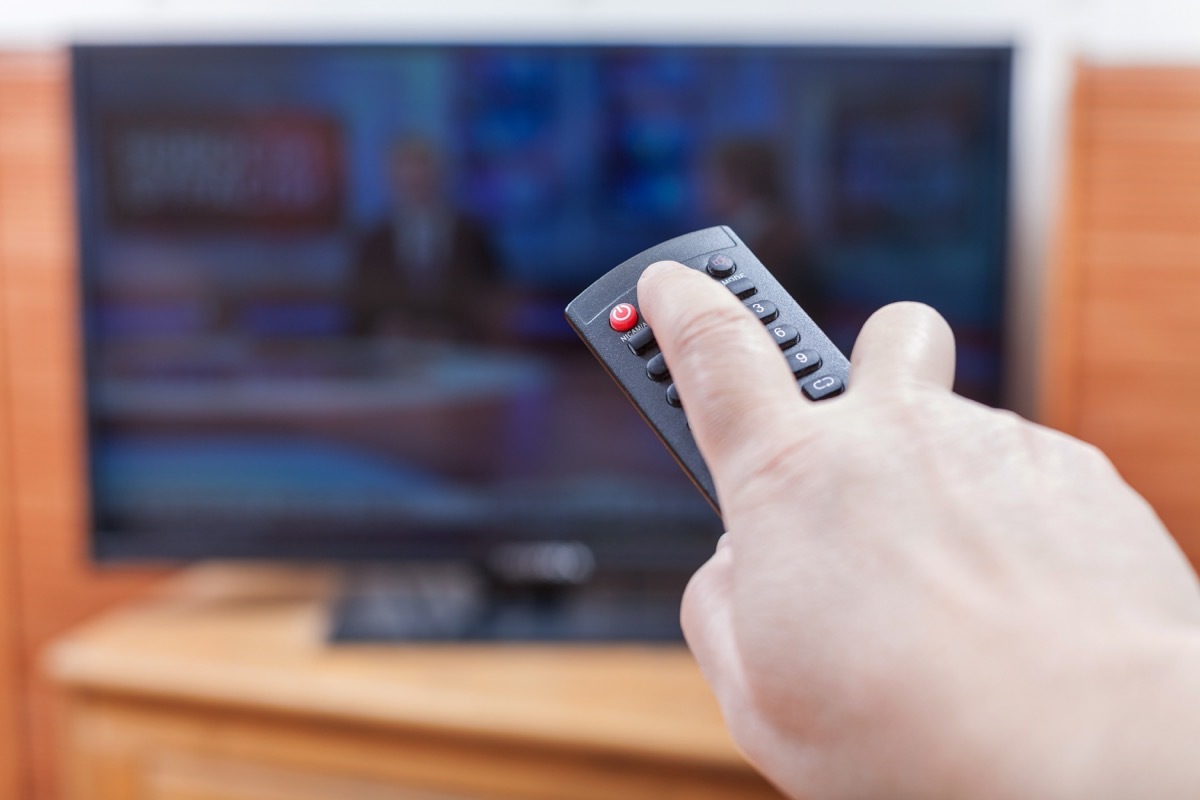 Person using a television remote to turn off their TV