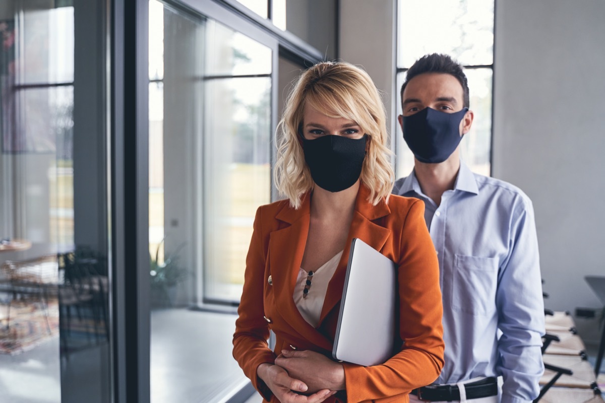 Front view of business people wearing protective masks in the office during the quarantine period