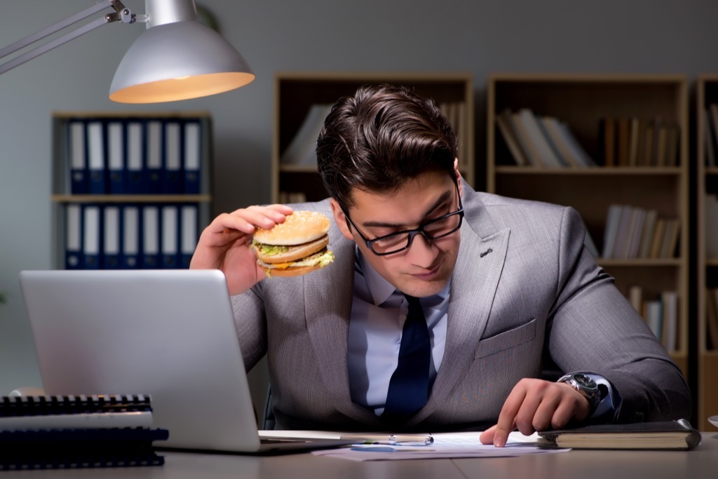 man eating a burger at work