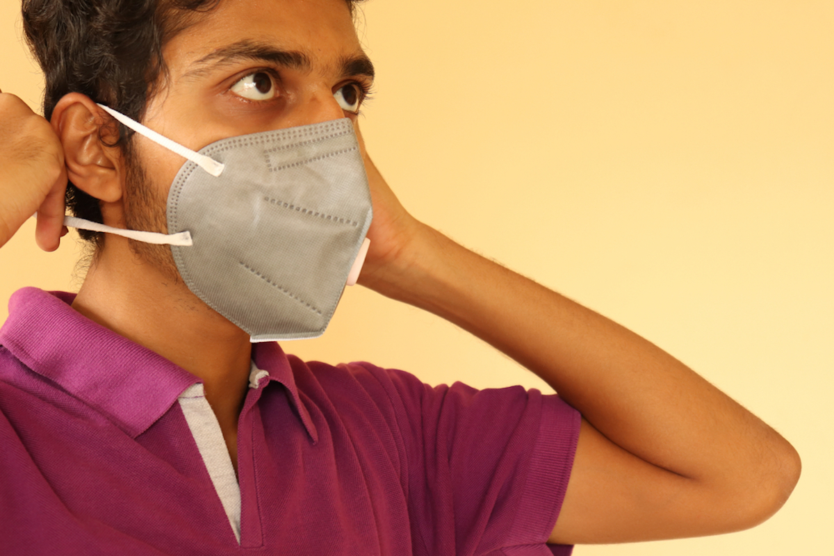 young man putting on ear loops of mask