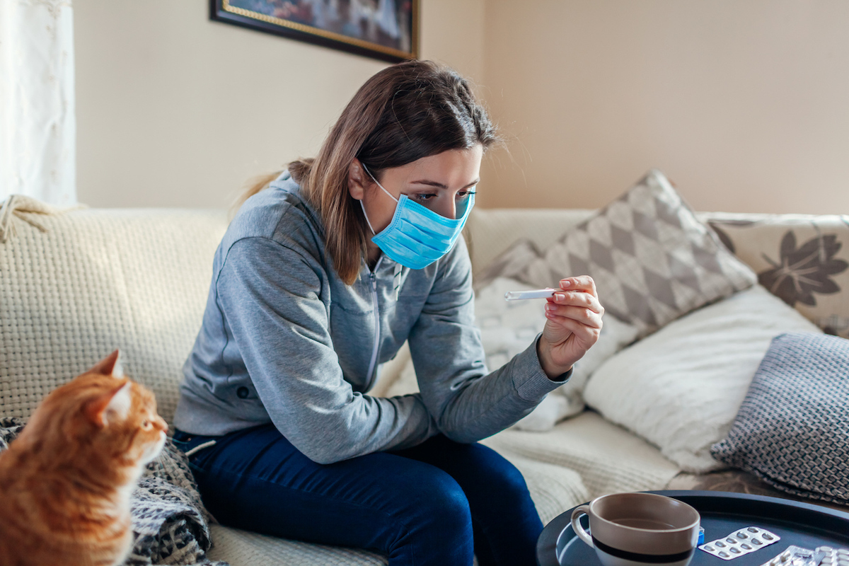 Woman checking thermometer for a fever.