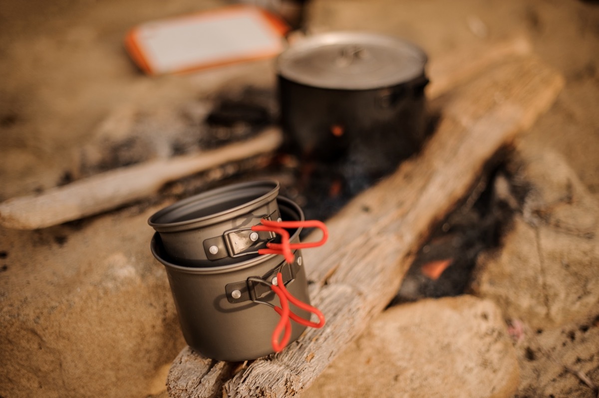 Set of metal one big and two small pans on the smoldering campfire