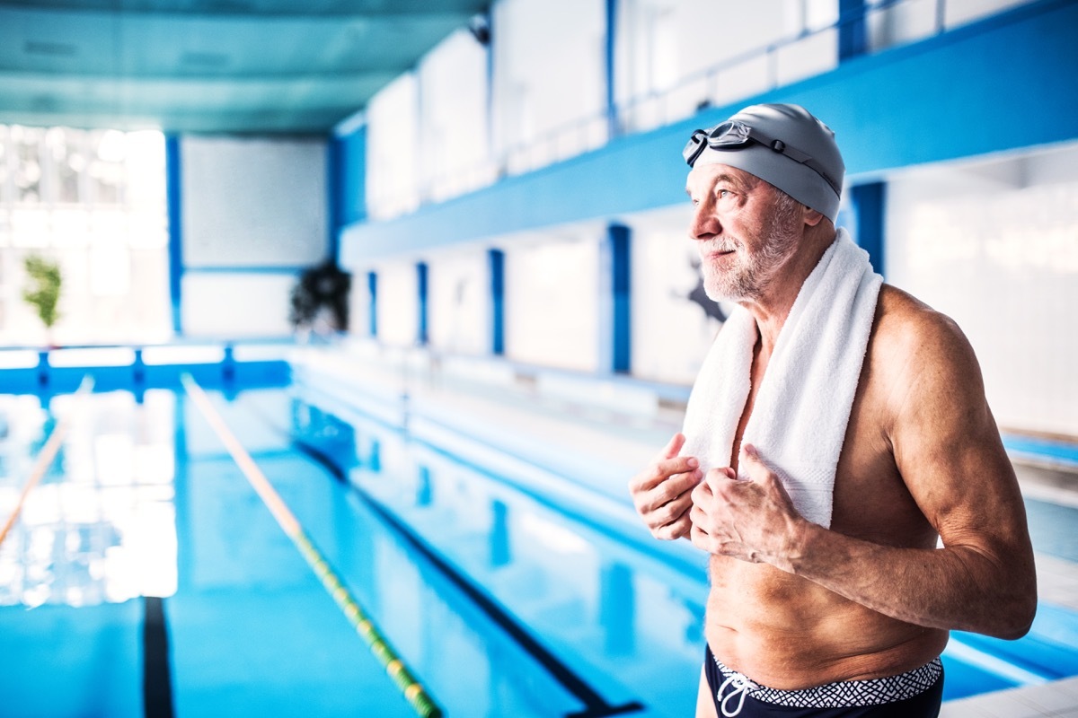 senior man standing by indoor pool