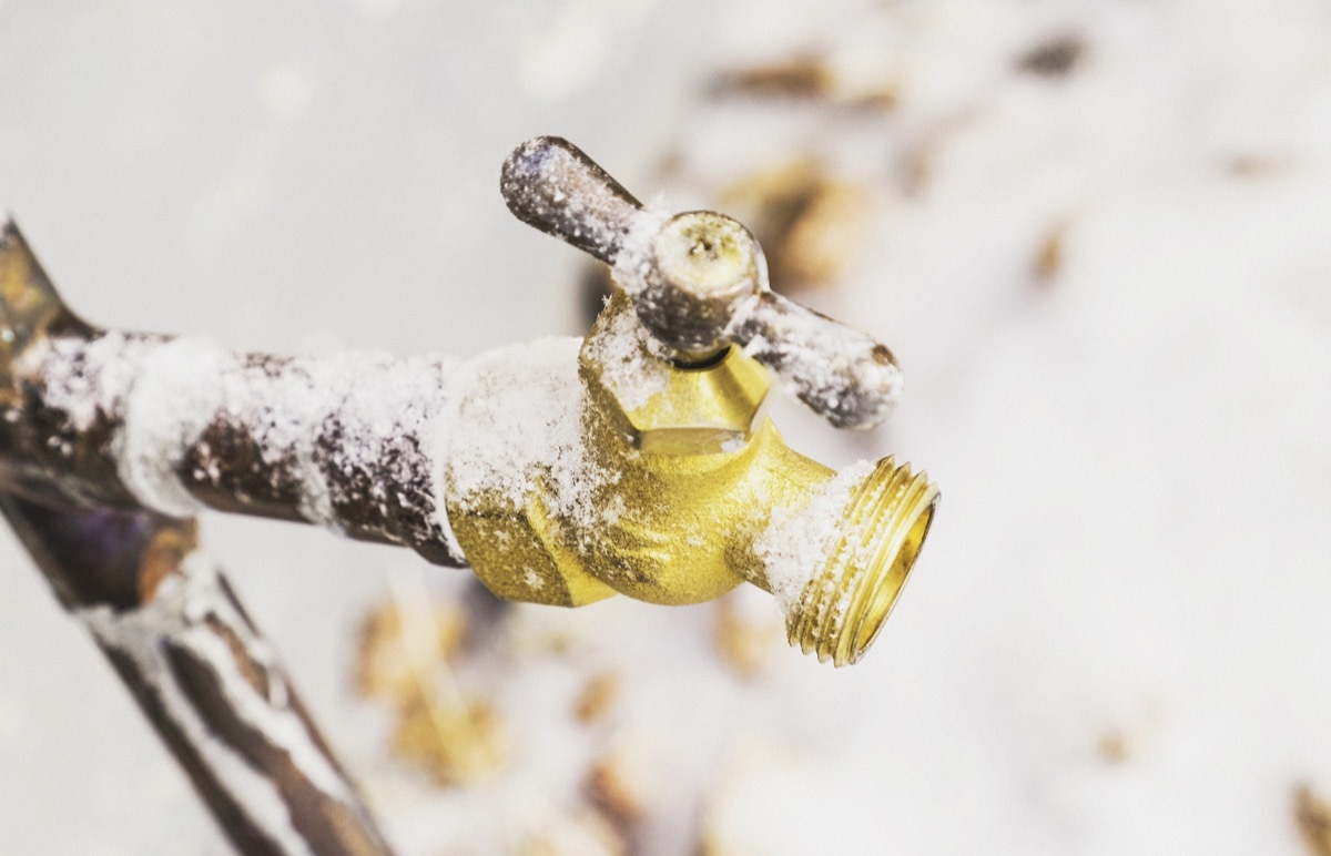 Frozen outdoor water faucet covered in snowflakes