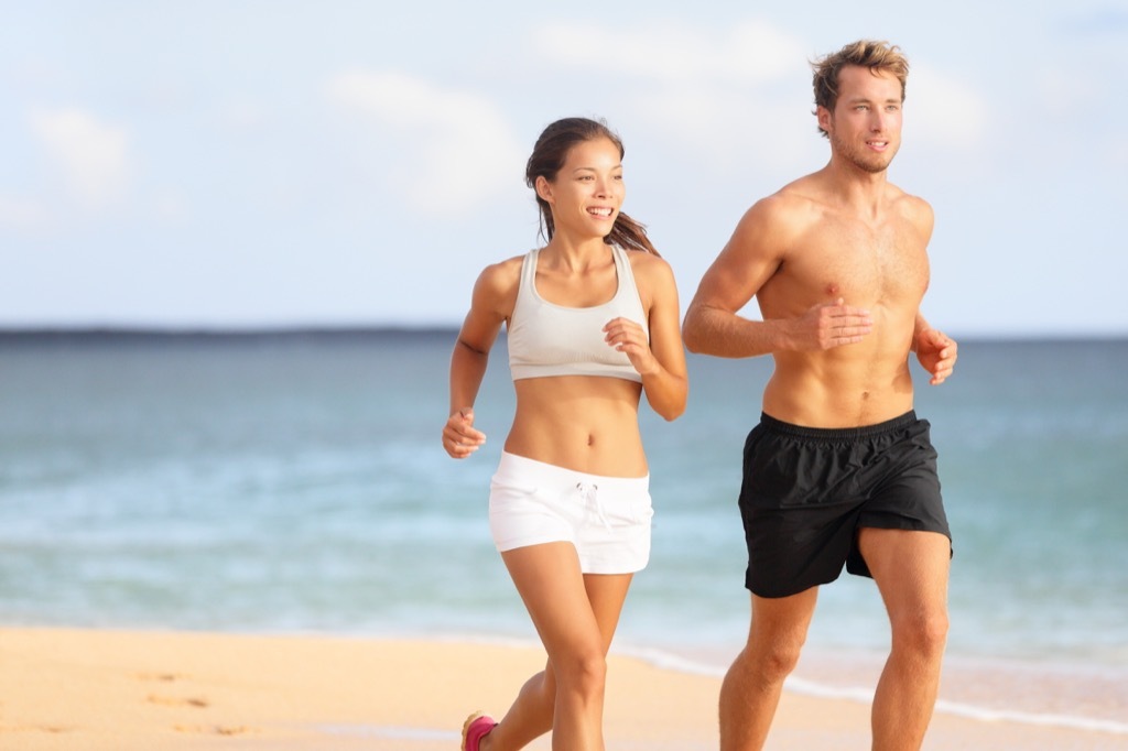 man and woman couple running at the beach