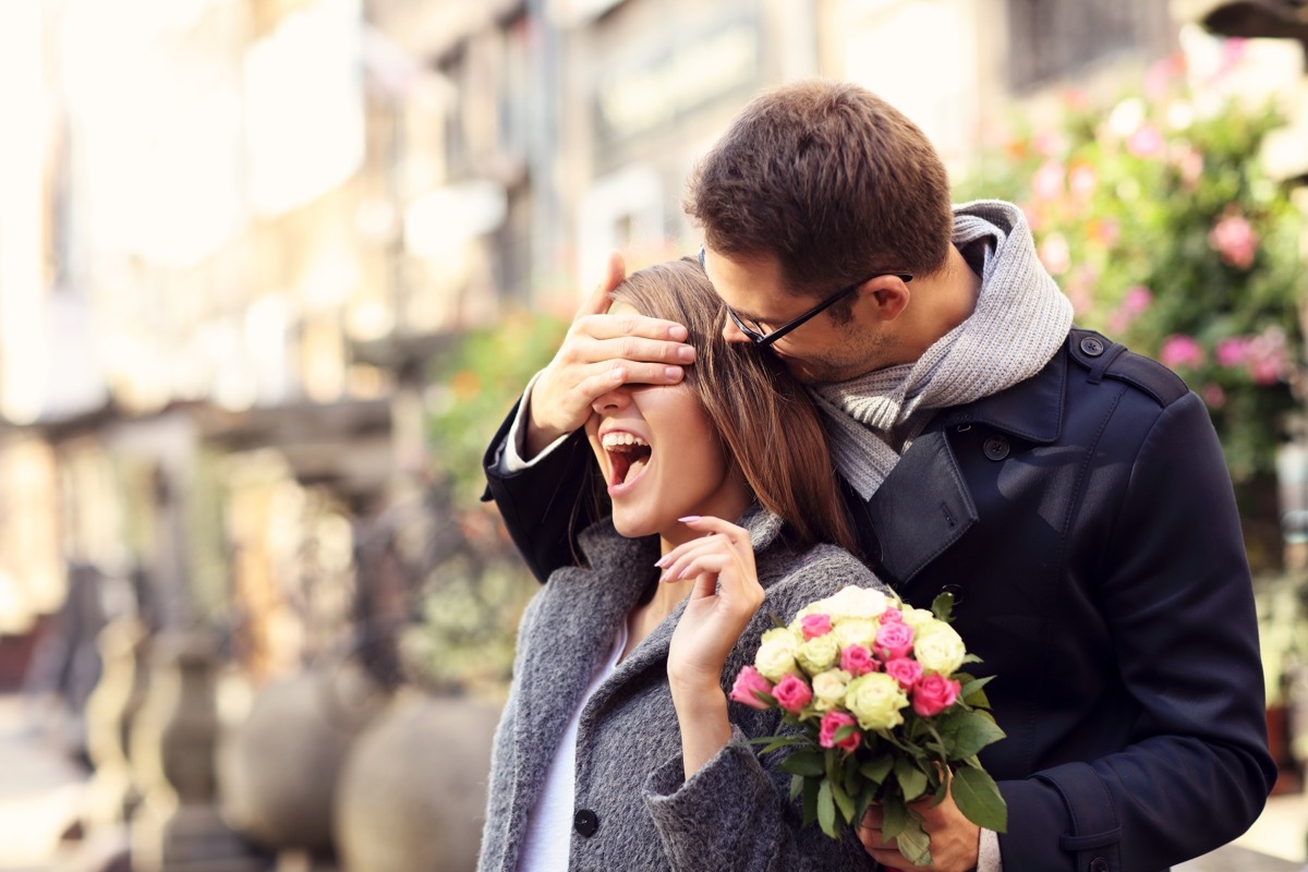 Man surprising woman with flowers