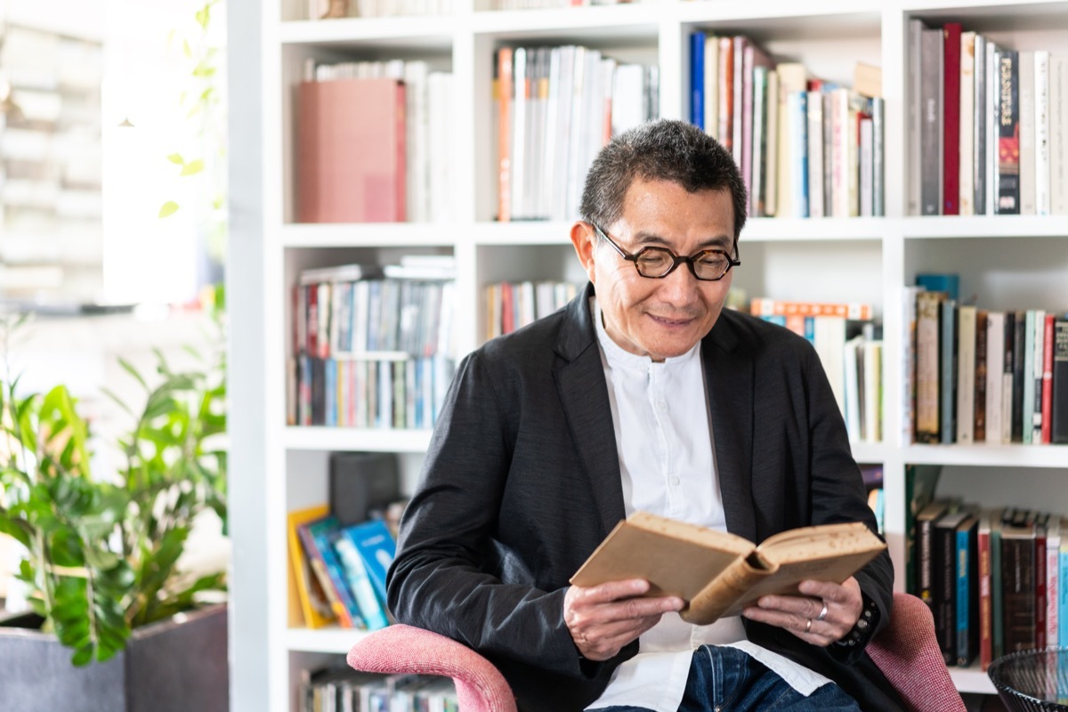 senior Chinese man holding a book and looking at camera.