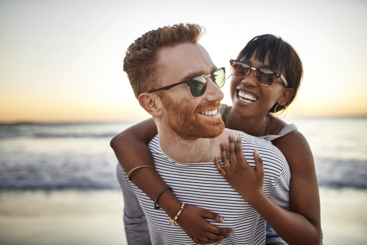 A young heterosexual couple hugging on the beach at sunset.