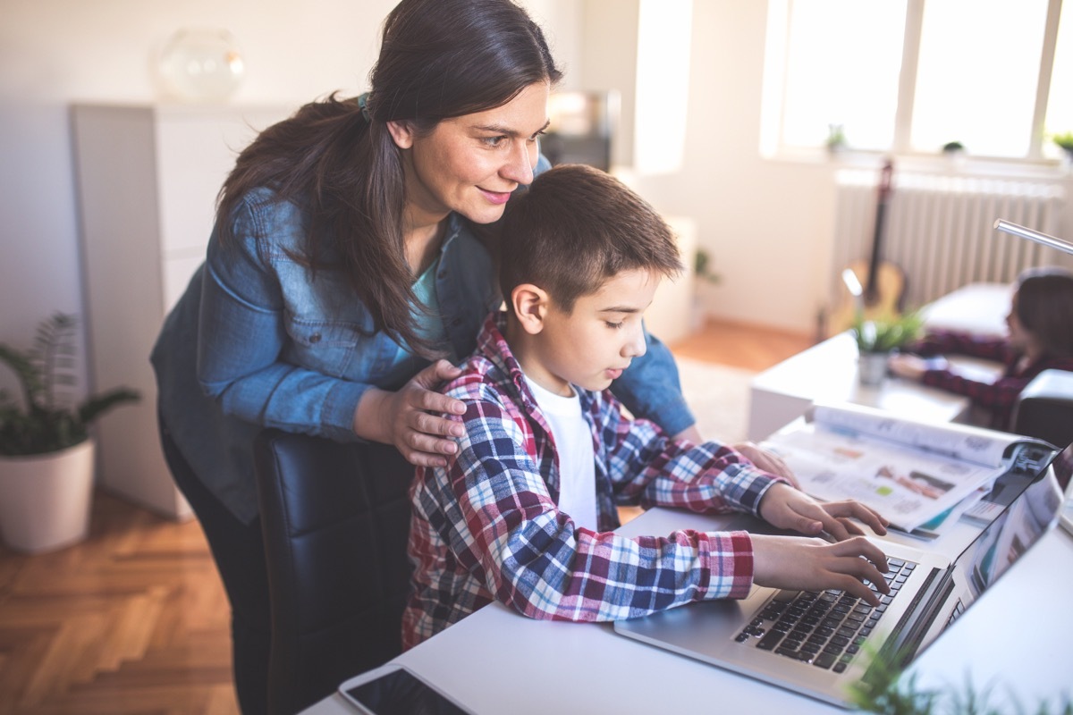 Mother helps son how to use a lap top and internet