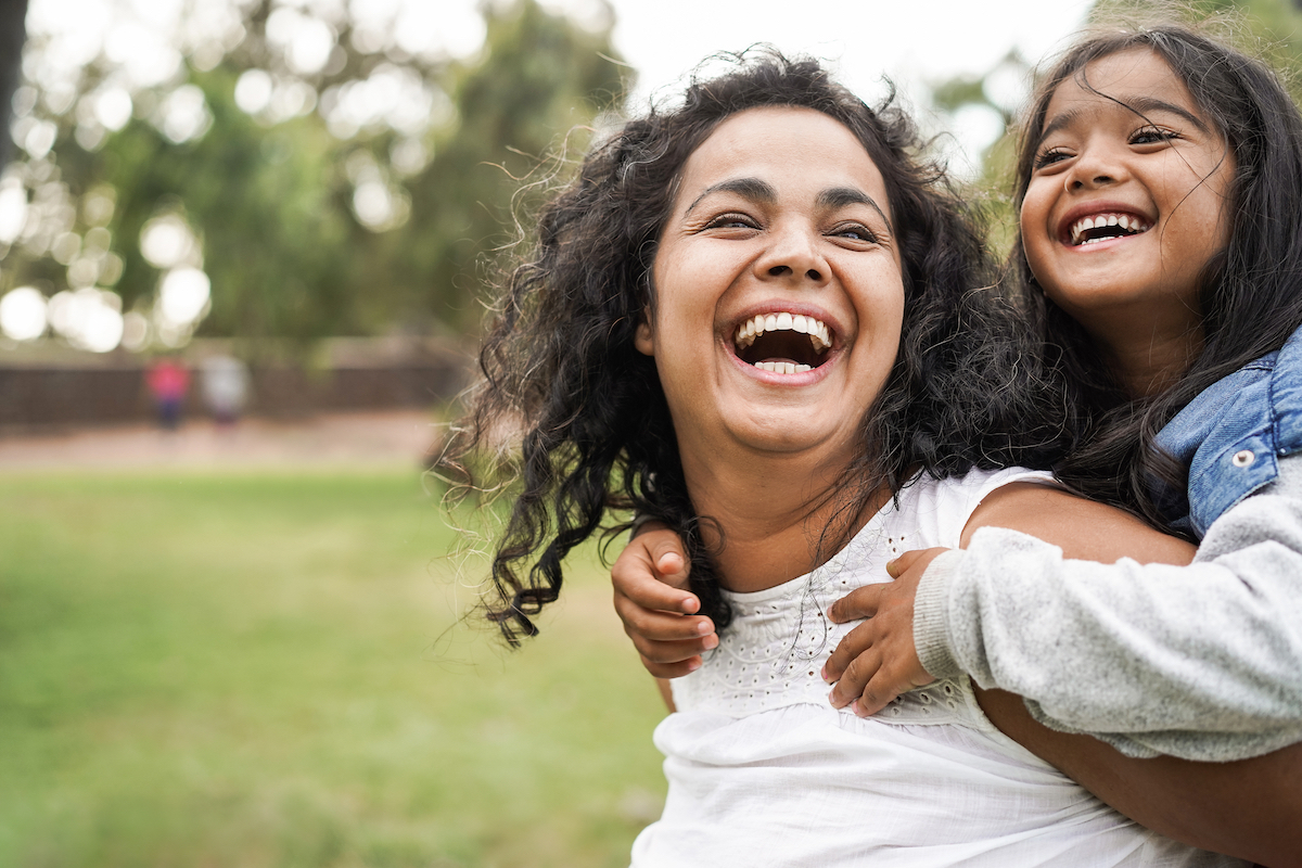 Happy mother and daughter playing outside and laughing