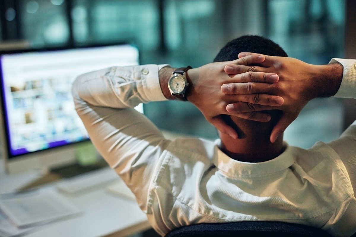 Rearview shot of a young businessman taking a break at his desk during a late night in a modern office