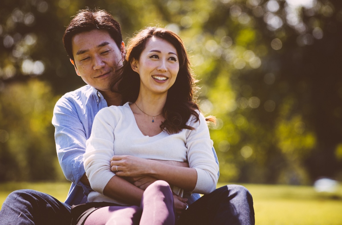 middle aged asian couple sitting in grass