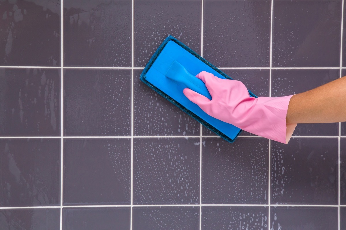 pink gloved hand scrubbing shower