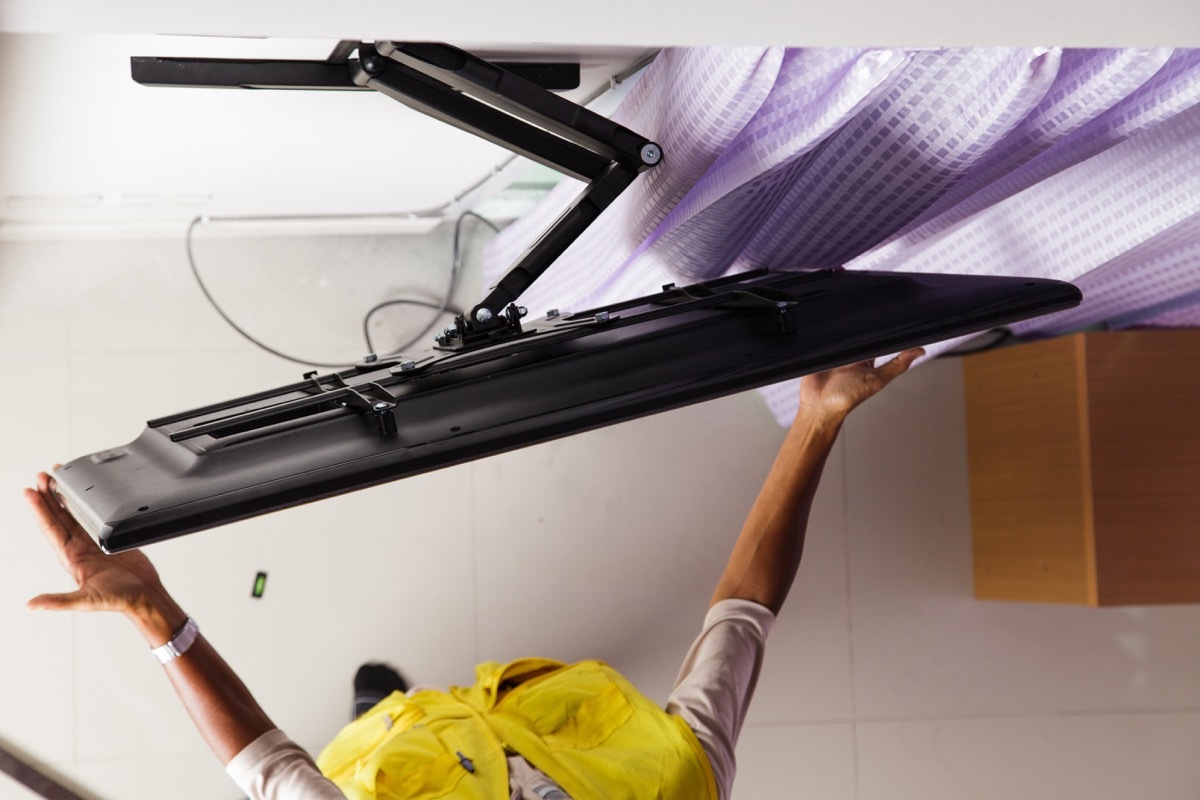 person mounting a flat-screen tv on a wall