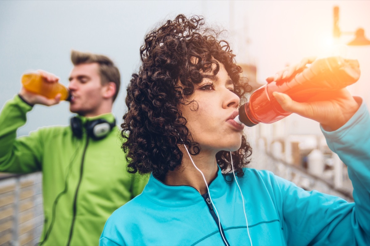 Man and woman drinking energy drink from bottle after fitness sport exercise