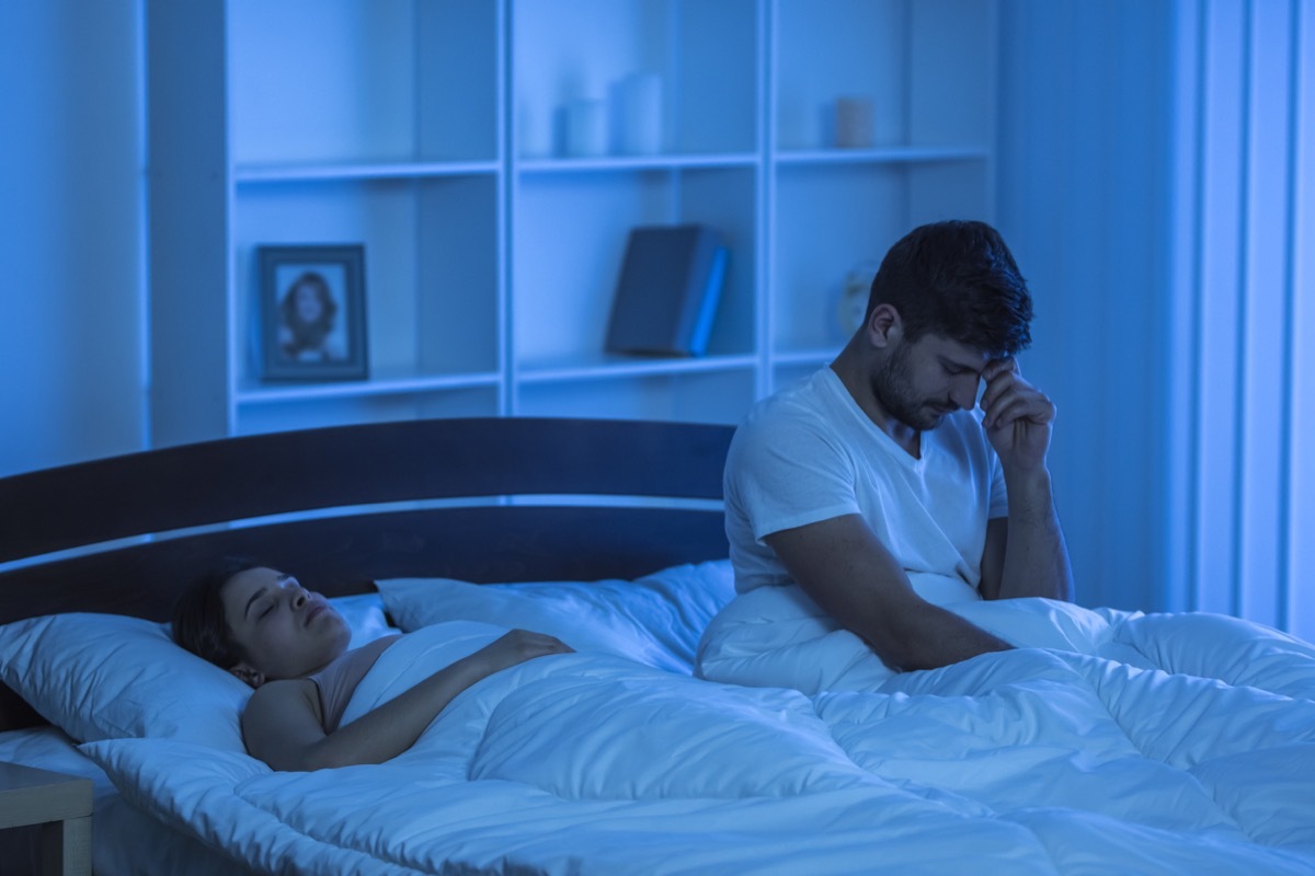 Man with headache sits in bed